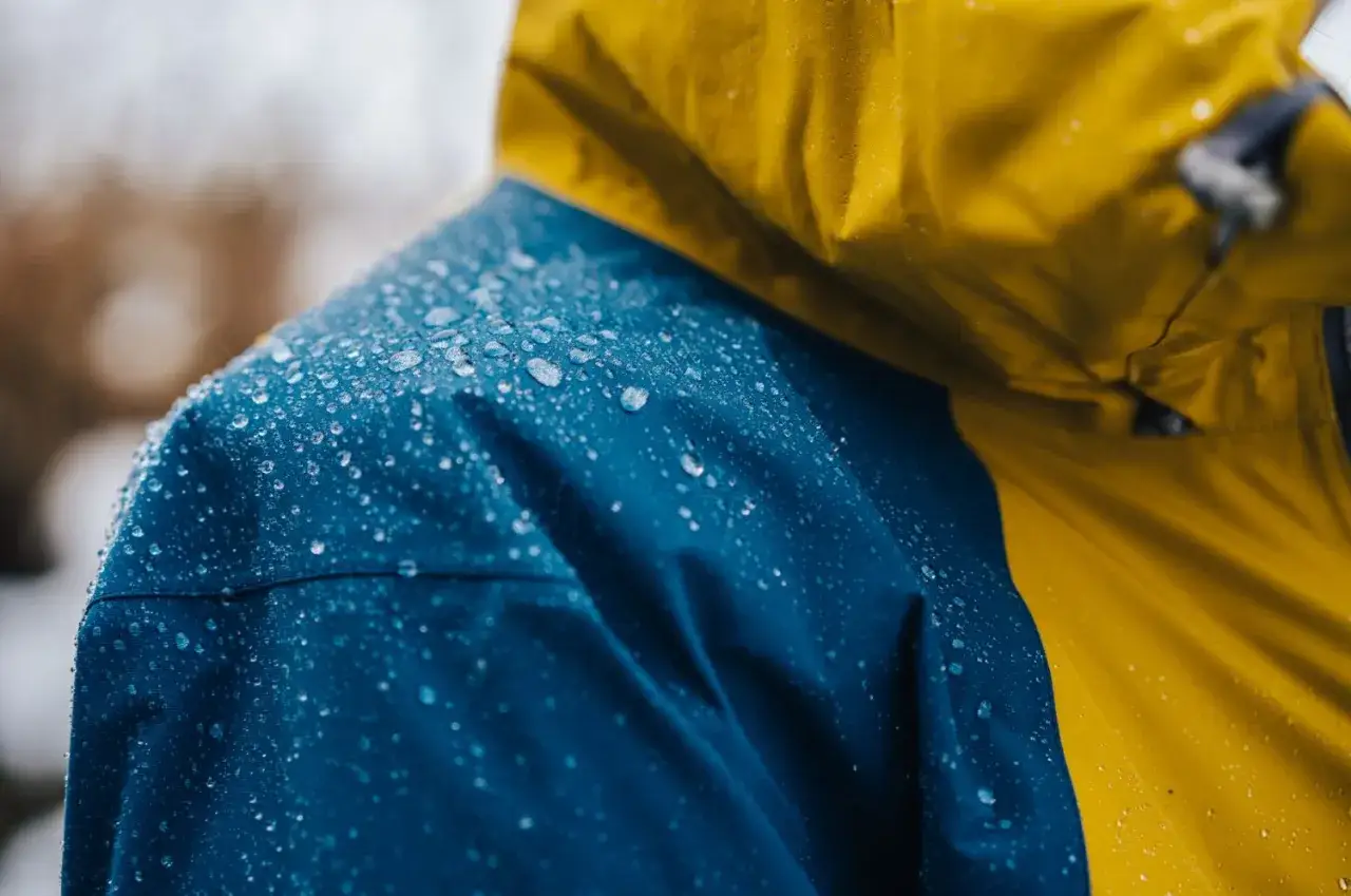Vattenp&auml;rlor p&aring; en bl&aring; och gul jacka, bevis p&aring; effektiv gore tex impregnering.