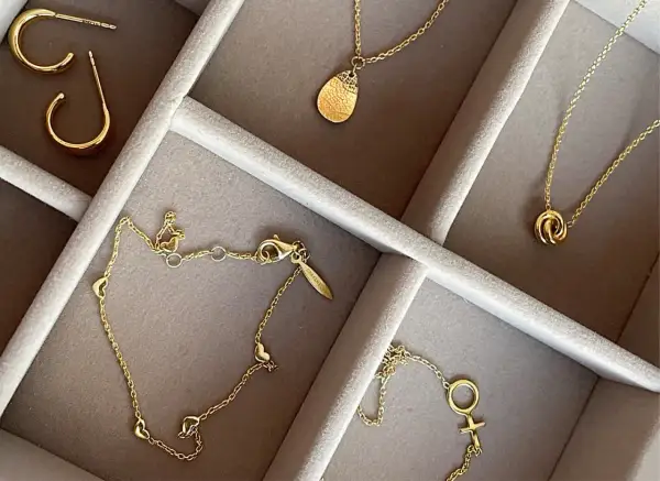 Ett urval av eleganta guld smycken herr: örhängen, halsband med hängsmycken och ett armband med hjärtan.