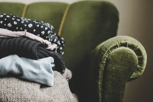 En hög med kläder ligger på en grön soffa. Kanske dags för lite dry clean hemma?