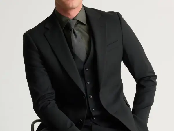 Man i svart kostym med svart skjorta och slips. Elegant och stilren klädsel.