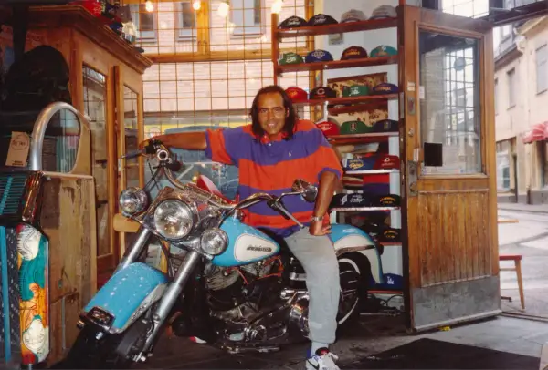 Man på motorcykel i en butik med kepsar, kanske en del av "Broadway & Sons" sortiment.