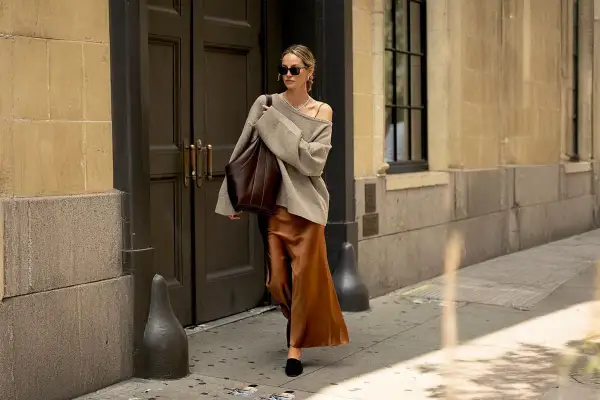 En kvinna går på gatan i en elegant outfit där brunt och svart ihop skapar en sofistikerad look.