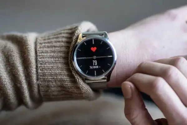 En person bär en elegant Garmin-klocka med en röd hjärtsymbol och puls på skärmen. En av de bästa herrklockor för den hälsomedvetne.