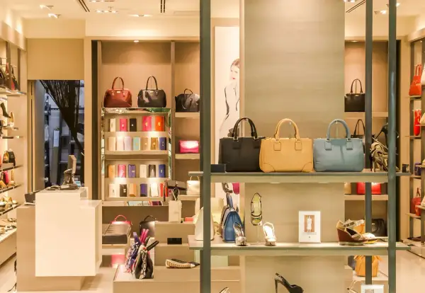 Ett skyltfönster med väskor och skor från italienska modehus. Lyxiga accessoarer visas upp i en elegant butiksmiljö.
