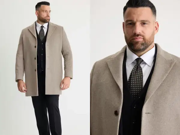 Man i beige jacka till kostym, med svart väst och mönstrad slips.