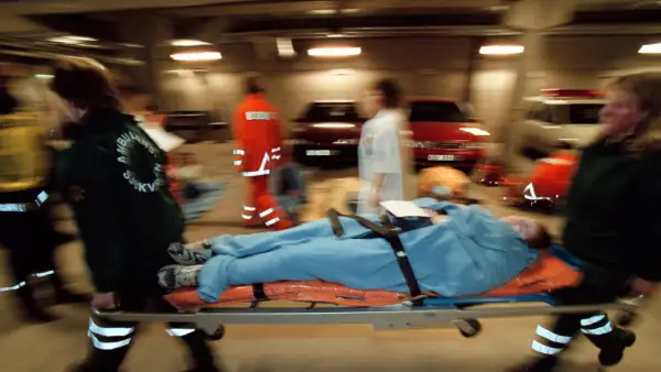 Ambulanspersonal bär en patient på bårbil. Tänk om dragkedja uppfinnare kunde se hur snabbt de arbetar.